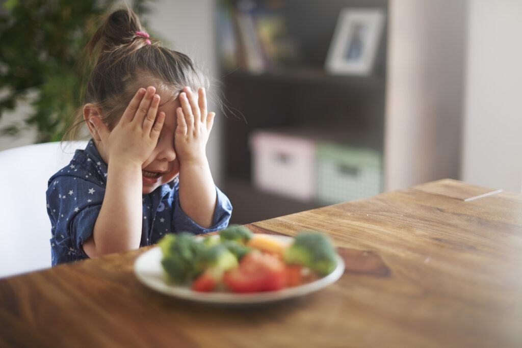 Niño con FAOD mostrando rechazo a la comida en la mesa, acompañado por sus padres.