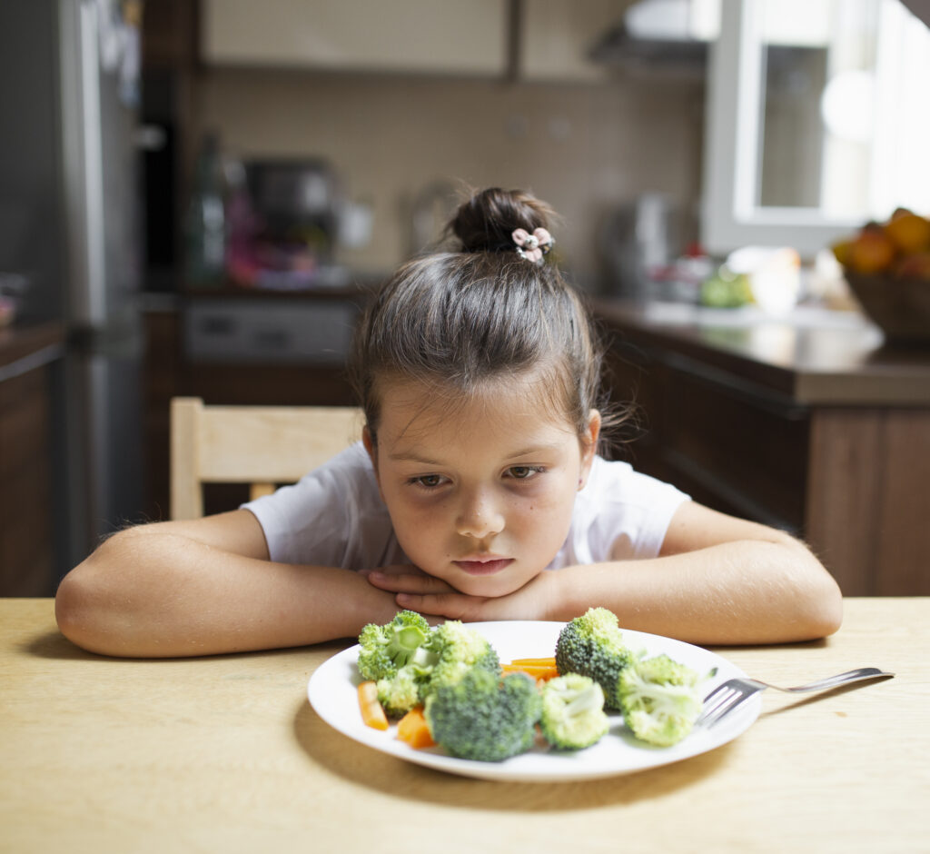 Niño con FAOD mostrando rechazo a la comida en la mesa, acompañado por sus padres.
